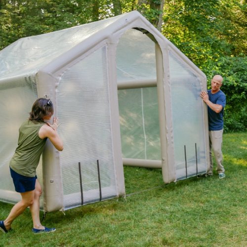 Two people lifting a HAVN inflatable greenhouse panel into place